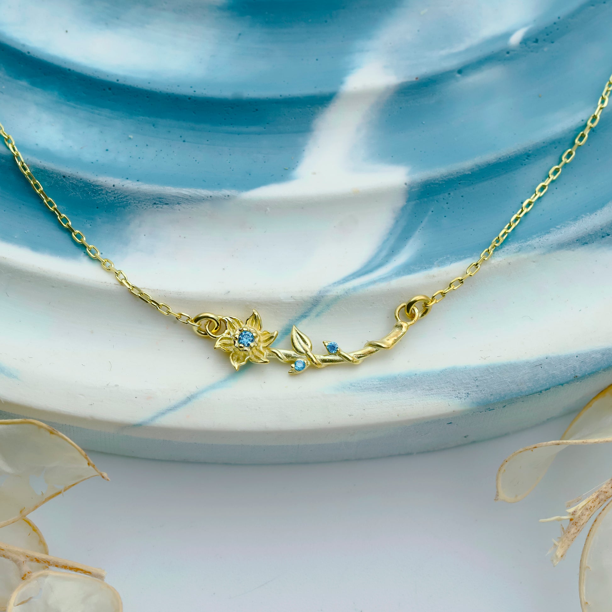 Gold necklace with floral design on a ceramic plate