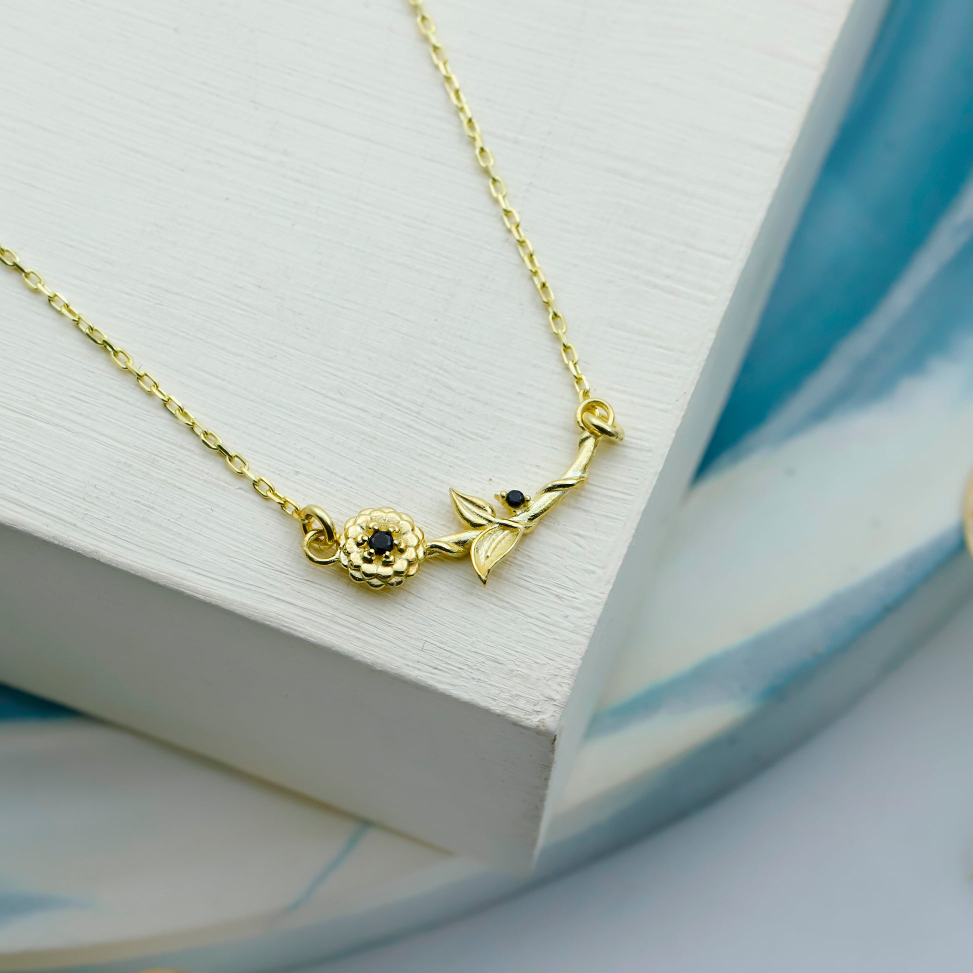 Gold necklace with floral design on a white surface