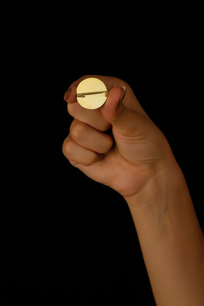 A gold  brooch placed in a hand.