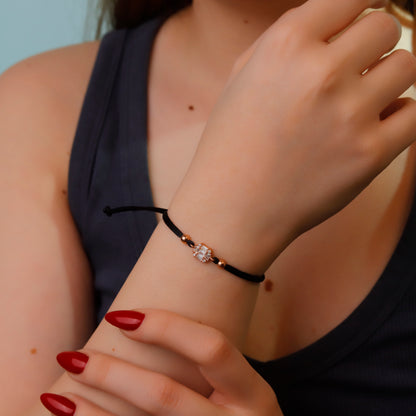 Close-up of a person wearing a black bracelet with a clear gemstone on their wrist.