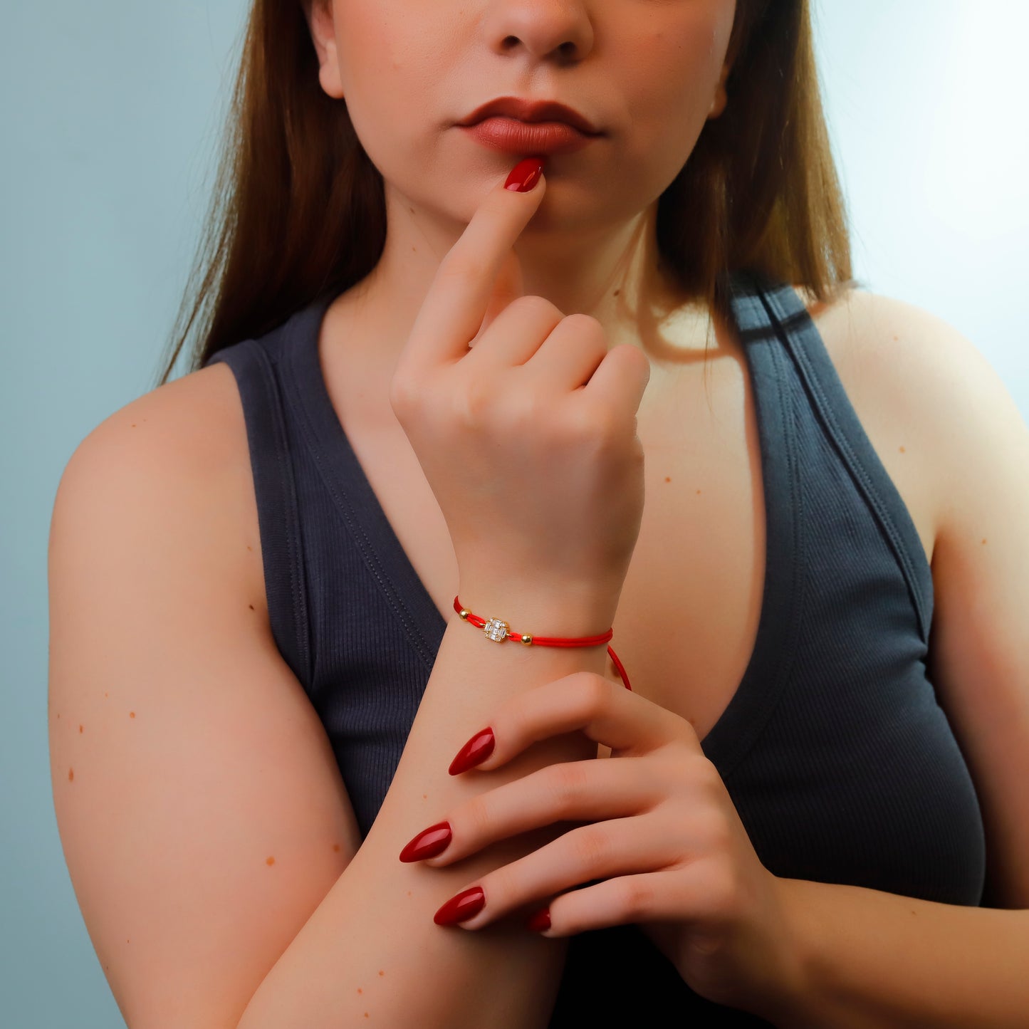 Woman with red nail polish and a red bracelet思考