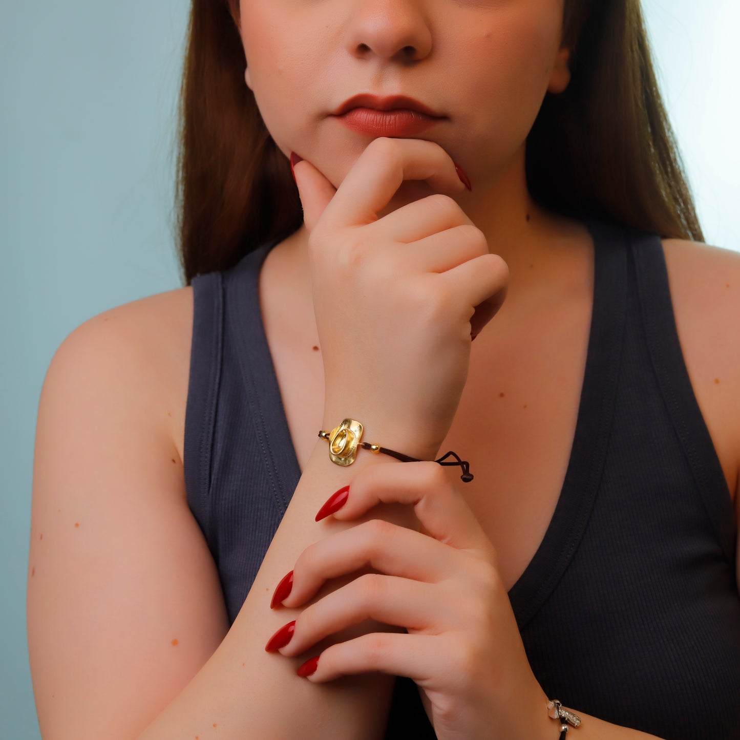 Woman wearing a gold bracelet with a blue background