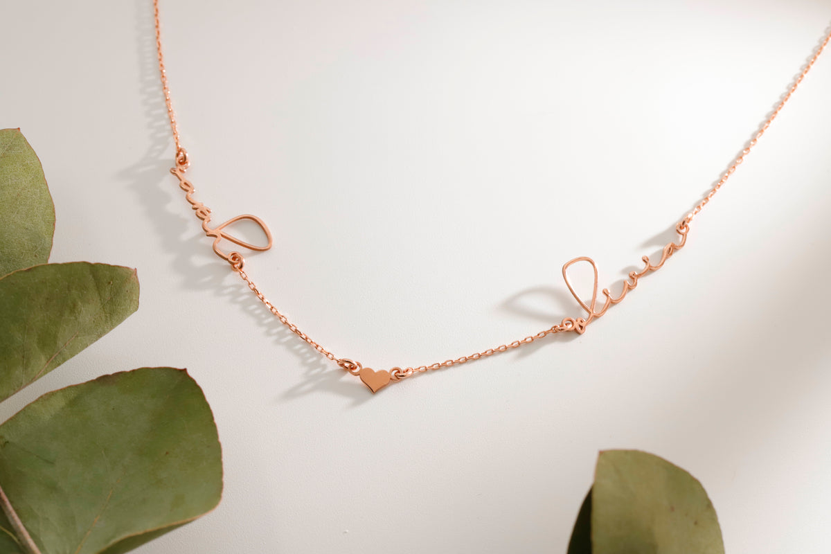 Rose gold necklace on a light background with green leaves