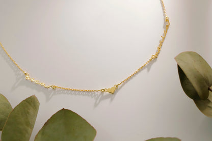 Gold necklace on a white background with green leaves