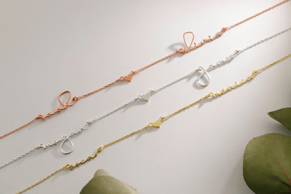 Three gold necklaces on a light gray background with green leaves.
