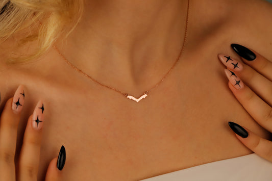 Necklace on a person's neck with hands touching the skin, wearing black nail polish with star designs.