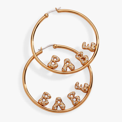 Rose gold hoop earrings with 'Babe' lettering on a white background