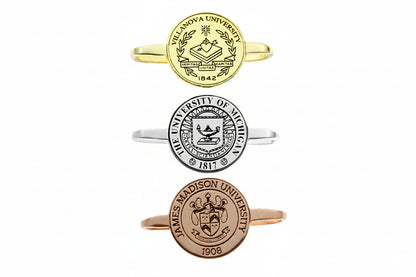 Three university-themed rings in gold, silver, and rose gold on a white background.