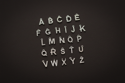 Silver letter charms arranged in alphabetical order on a black background