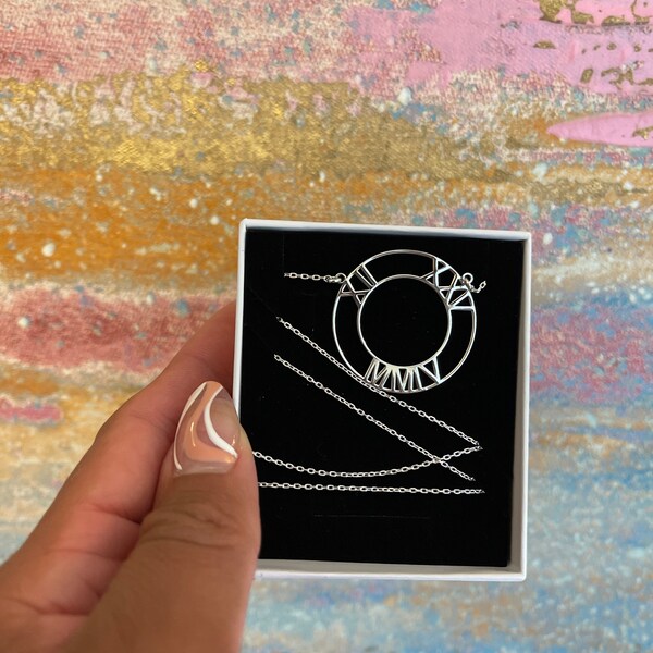 Hand holding a card with jewelry designs against a colorful, textured background