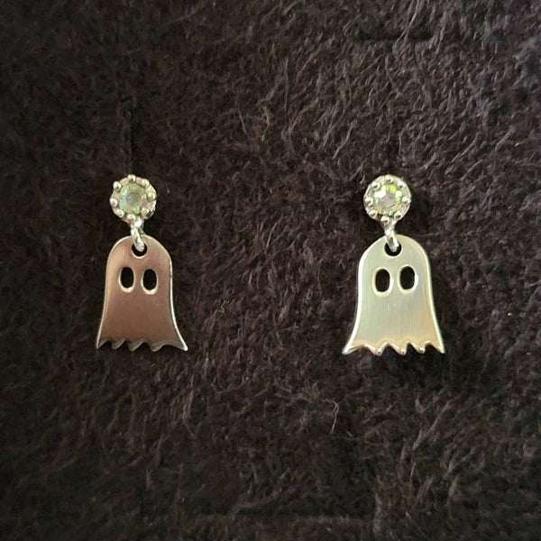Ghost-shaped earrings with clear gemstones on a dark textured background