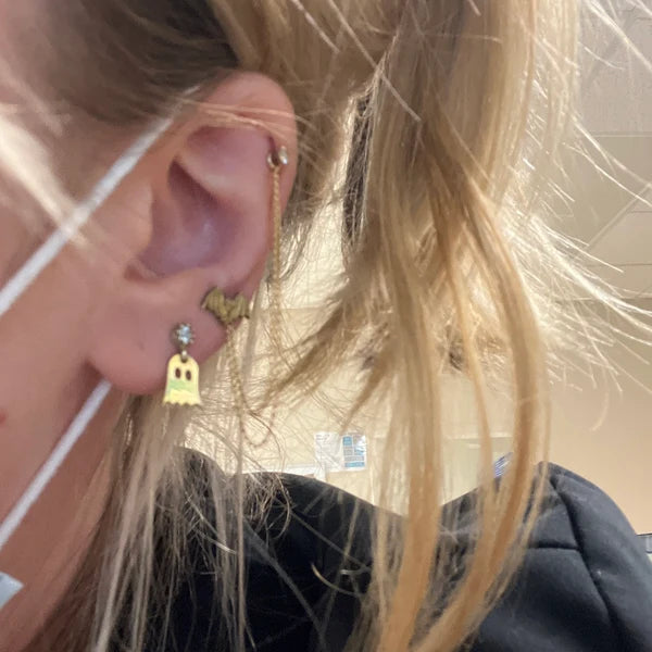 Close-up of a person wearing gold earrings with a blurred background