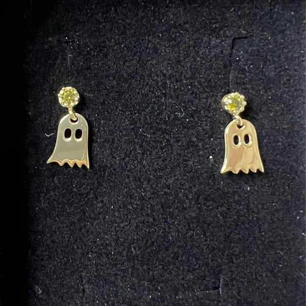 Ghost-shaped earrings with a yellow gemstone on a black background