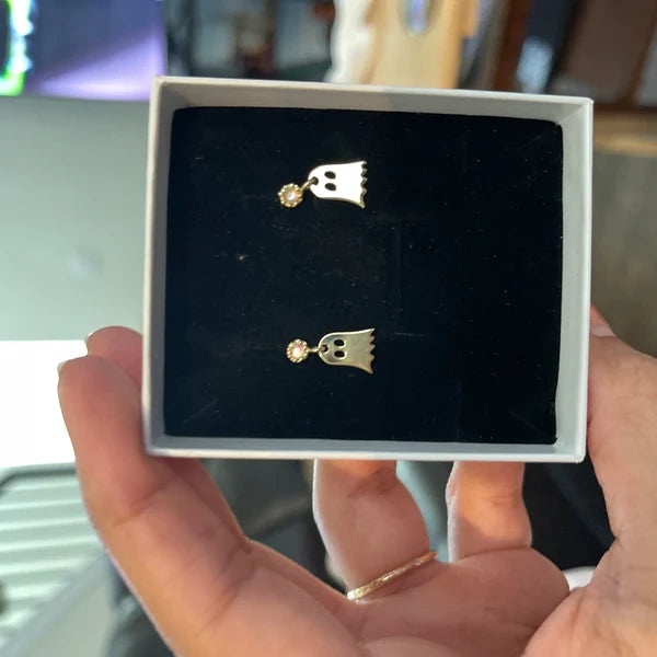 Gold crown-shaped earrings in a jewelry box held by a person.