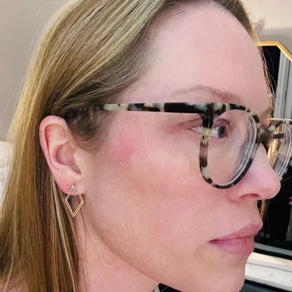 Close-up of a person wearing glasses with a geometric earring.