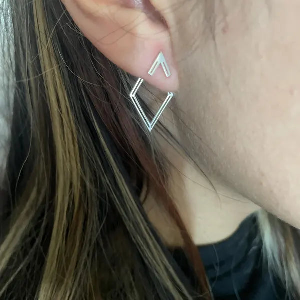 Close-up of a person wearing a silver geometric earring.