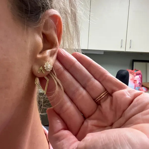 Close-up of a person wearing gold earrings with a blurred background
