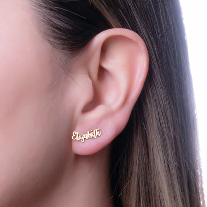 A close-up image of a person wearing a gold-toned stud earring with a custom name on it.