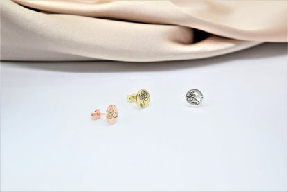 A close-up image of  a small gold-colored floral earring.