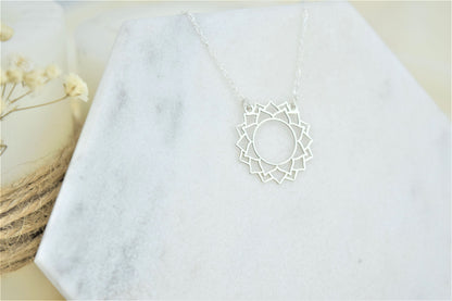 a silver-colored choker necklace with a geometric design, representing the Sahasrara Yoga chakra.