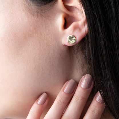 A close-up image of a woman's face with a small gold-colored floral earring in her ear.