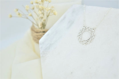 a silver-colored choker necklace with a geometric design, representing the Sahasrara Yoga chakra.
