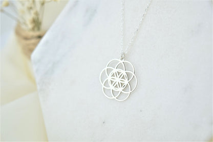 a silver pendant necklace with a floral seed of life design.