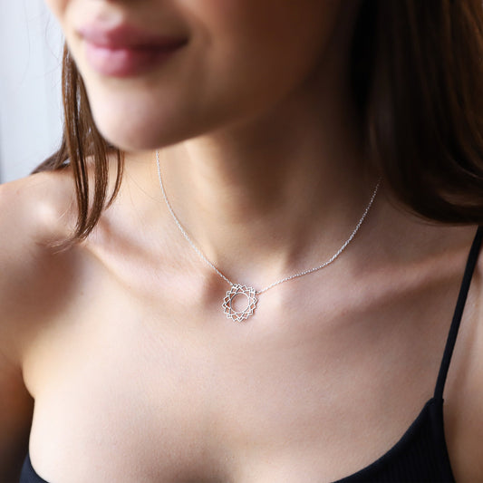 a silver-colored choker necklace with a geometric design, representing the Sahasrara Yoga chakra.