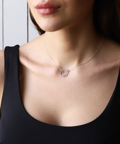 A person wearing a silver chakra necklace with a geometric design around the neck.
