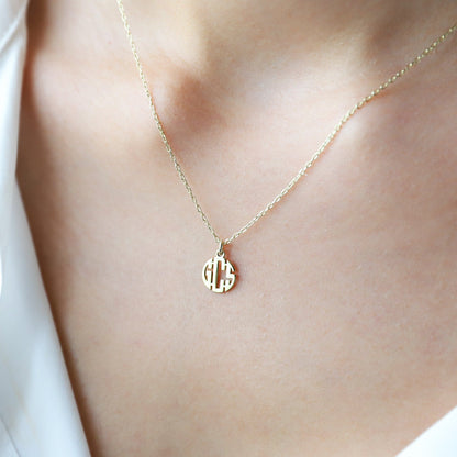 Gold necklace with a round pendant on a person wearing a white top.