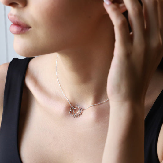 A person wearing a silver chakra necklace with a geometric design around the neck.