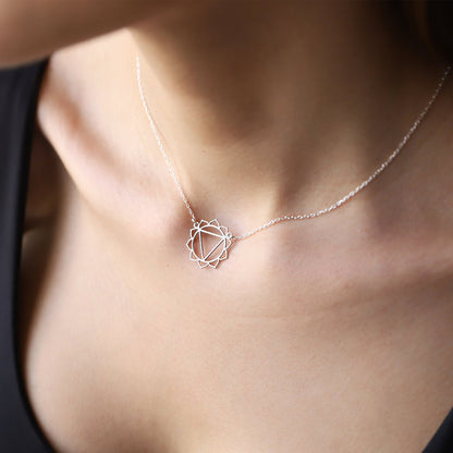 A person wearing a silver chakra necklace with a geometric design around the neck.