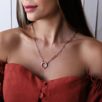 A person wearing a gold link chain necklace with a paperclip-shaped pendant and Sailor Lock.