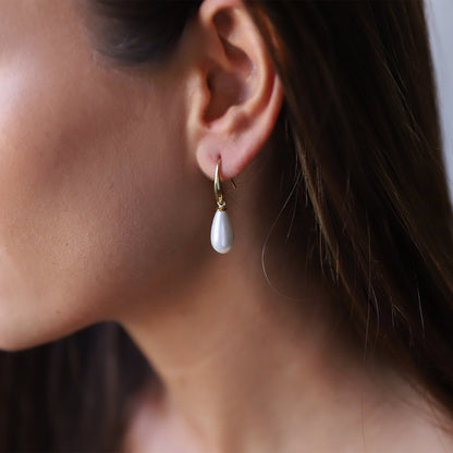 A woman wearing drop pearl earrings,