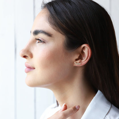 A close-up image of a person wearing a gold-toned stud earring with a custom name on it.
