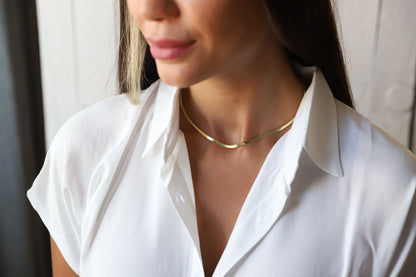 Woman wearing a gold necklace with a blurred background