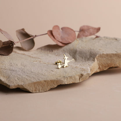 A close-up image of aa small gold stud earring with a witch design