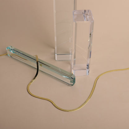 Clear glass lamp with gold cord on a beige background