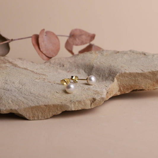 Pearl earrings on a stone surface with a soft background