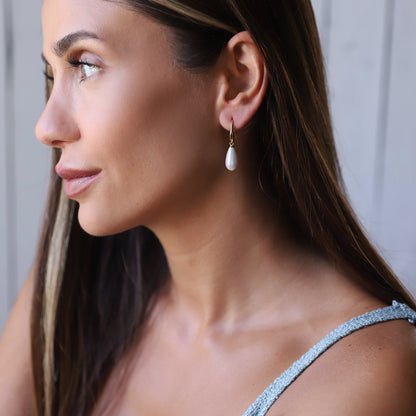 A woman wearing drop pearl earrings,