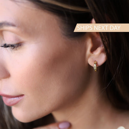 A close-up image of a person wearing a silver hoop earring with a small gold detail on the hoop.