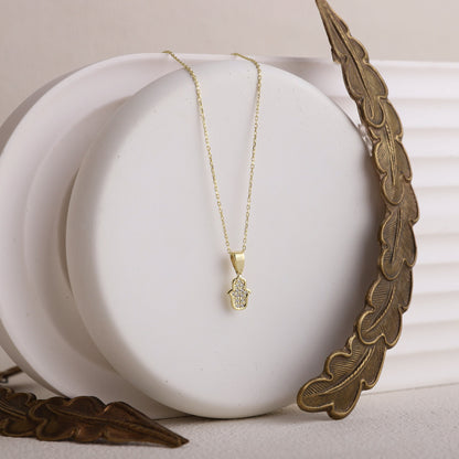  a gold-colored Hamsa Charm Necklace with a Hand of Fatima design and pave CZ diamonds.