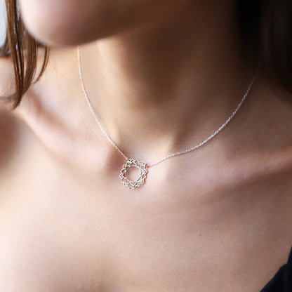 A person wearing a silver-colored choker necklace with a geometric design, representing the Sahasrara Yoga chakra.