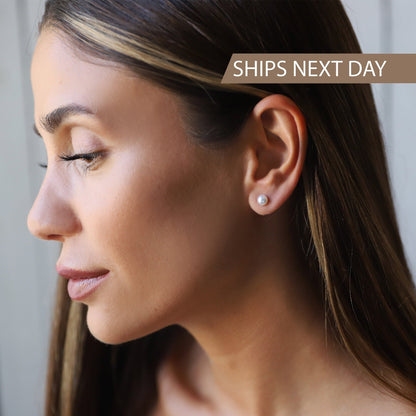Close-up of a woman wearing pearl earrings with text 'SHIPS NEXT DAY' on a neutral background