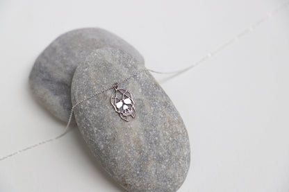 A close-up image of a person wearing a sterling silver necklace with a sugar skull pendant.