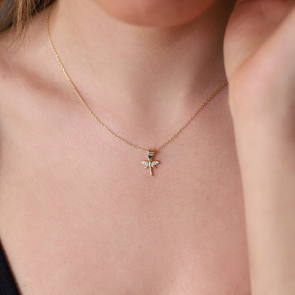 A close-up image of a woman wearing a gold-filled dragonfly necklace with a dainty pendant.