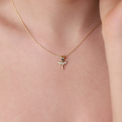 A close-up image of a woman wearing a gold-filled dragonfly necklace with a dainty pendant.
