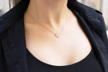 A person wearing a gold-colored necklace with an ornate pendant on a silver chain.