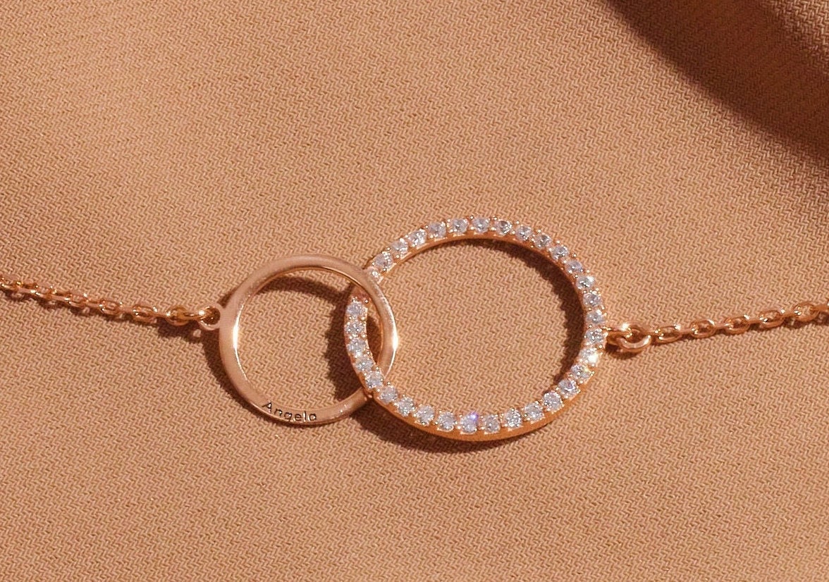 Rose gold bracelet with interlocking rings on a beige background