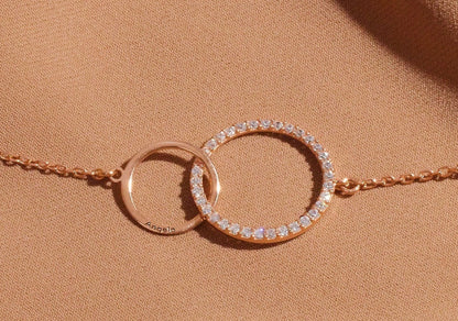 Rose gold bracelet with interlocking rings on a beige background
